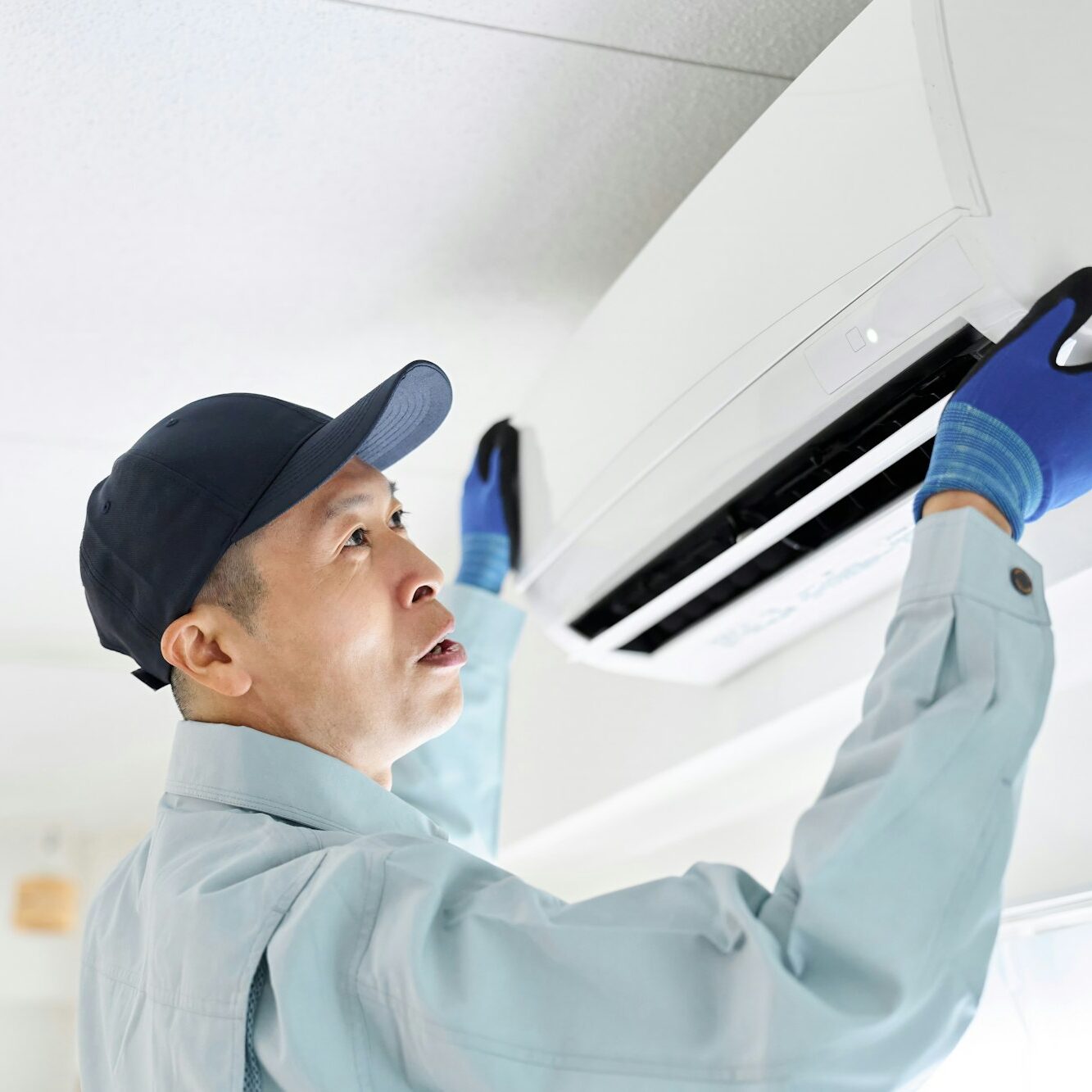 Asian worker inspecting air conditioner